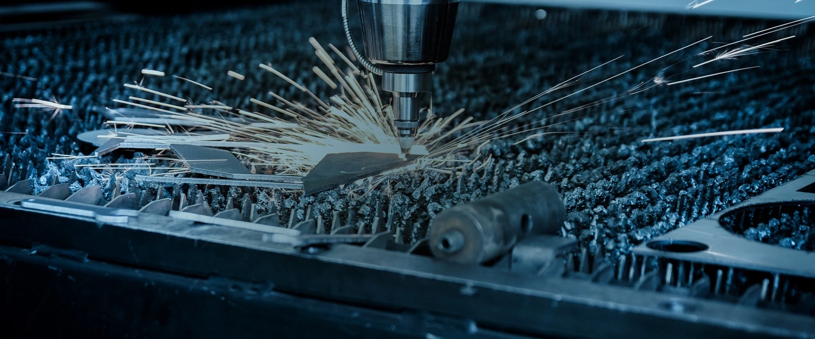 Industrielle Laserschneidmaschine beim Schneiden eines Metallblechs, sichtbare Funken beim Schneidvorgang.