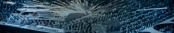 Industrielle Laserschneidmaschine beim Schneiden eines Metallblechs, sichtbare Funken beim Schneidvorgang.